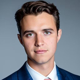 profesional headshot photo of Angelo Valle in a blue suit and peach colored tie